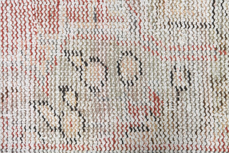 May include: Close-up of a woven rug with a textured pattern in shades of white, red, and black.