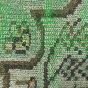 May include: A woven textile rug featuring a dense pile construction with a prominent green background. The surface displays intricate geometric and organic patterns rendered in dark brown, black, and lighter shades of green, creating a textured appearance.