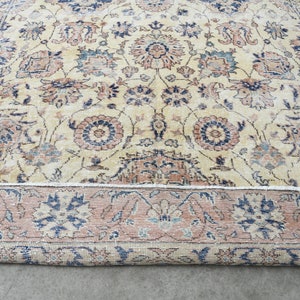 May include: A vintage rug with a cream background and a floral pattern in shades of blue, pink, and beige. The rug has a border with a repeating floral design.