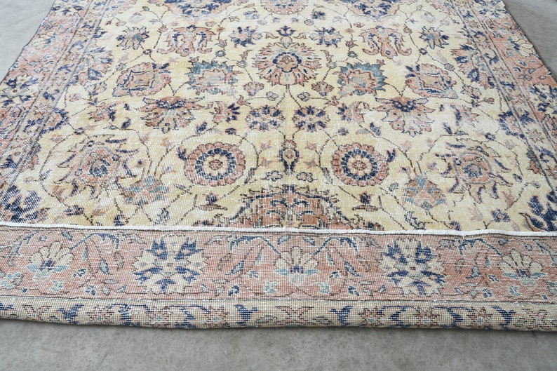 May include: A vintage rug with a cream background and a floral pattern in shades of blue, pink, and beige. The rug has a border with a repeating floral design.