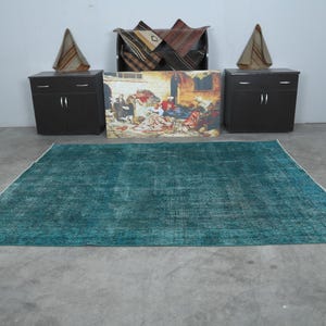 May include: A teal blue rug with a distressed, vintage look. The rug has a subtle pattern and is perfect for adding a touch of color and texture to any room.