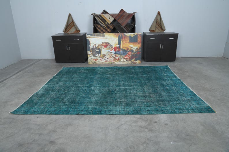 May include: A teal blue rug with a distressed, vintage look. The rug has a subtle pattern and is perfect for adding a touch of color and texture to any room.