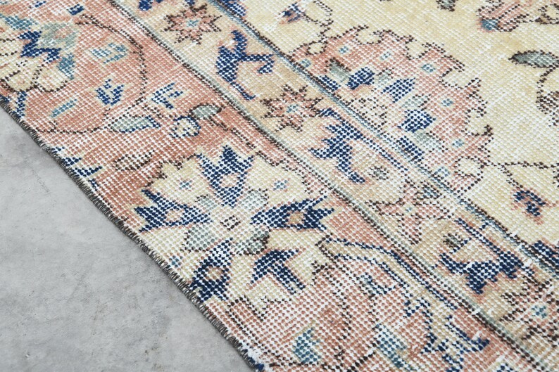 May include: Close-up of a vintage rug with a cream background and a repeating pattern of blue and pink floral designs.