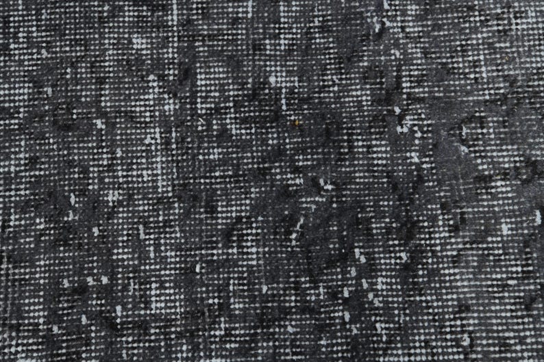 May include: Close-up of a black and white textured fabric with a subtle pattern. The fabric has a woven appearance and a slightly rough texture.