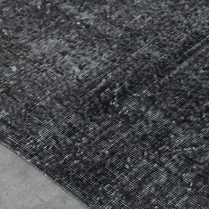 May include: A black and white patterned rug with a distressed look. The rug has a subtle, faded design.