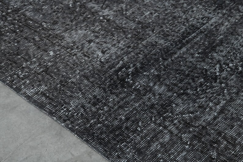 May include: A black and white patterned rug with a distressed look. The rug has a subtle, faded design.