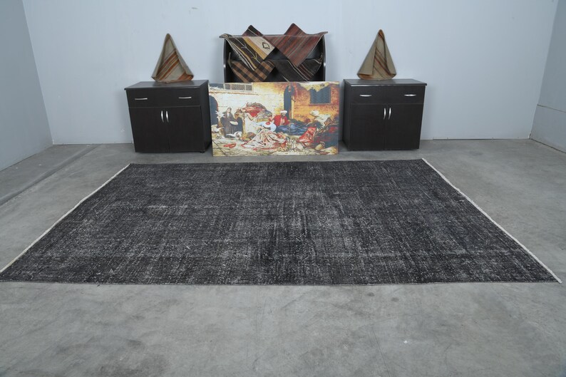 May include: A black and white distressed area rug with a subtle pattern. The rug is laid out on a gray concrete floor.