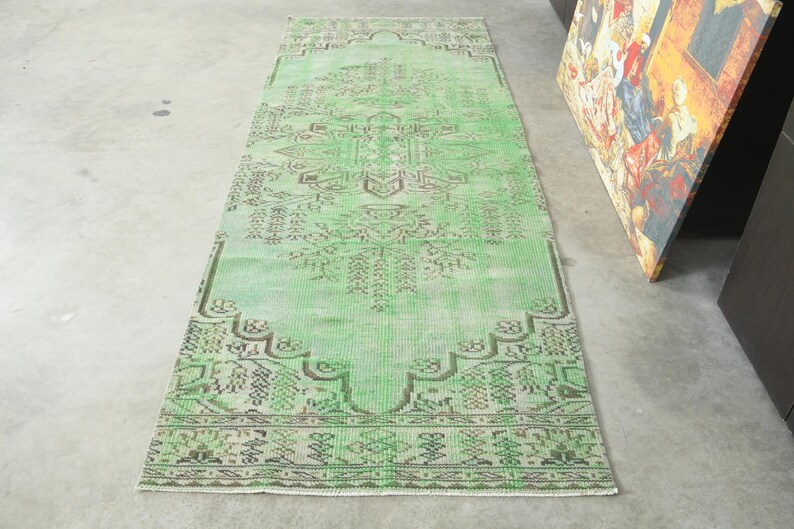 May include: A rectangular runner rug featuring a vibrant mint green base color with intricate, symmetrical geometric patterns in dark brown. The design includes a central medallion and detailed border motifs, creating a balanced visual composition.