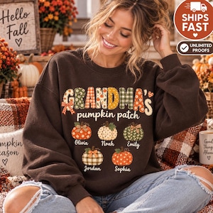 May include: A dark brown crewneck sweatshirt featuring the text "GRANDMA'S pumpkin patch" in a decorative font. Below the text are five illustrated pumpkins with various patterns, each labeled with the names Olivia, Noah, Emily, Jordan, and Sophia.