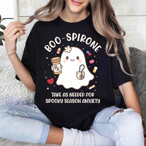 May include: Black t-shirt with the text "BOO-SPIRONE" and a cute ghost graphic holding a prescription bottle and stethoscope. The shirt also says "TAKE AS NEEDED FOR SPOOKY SEASON ANXIETY".
