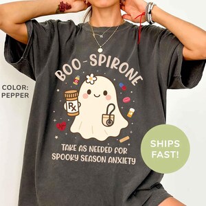 May include: Pepper-colored t-shirt with a graphic of a friendly ghost holding a prescription bottle and a stethoscope. The text reads "BOO-SPIRONE" and "TAKE AS NEEDED FOR SPOOKY SEASON ANXIETY."
