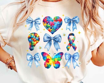May include: A white t-shirt with a blue, white, and rainbow puzzle piece heart, lightbulb, butterfly, and ribbon. The design is surrounded by blue bows.