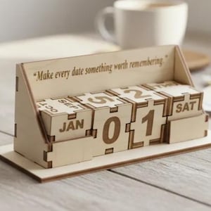 May include: A wooden perpetual calendar showing the date 01 January. The light brown calendar has the quote "Make every date something worth remembering." The calendar is on a wooden surface. The measurements are in centimetres.