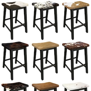 May include: Set of nine black bar stools with cowhide seat cushions. The cushions feature a variety of patterns, including brown and white, black and white, and brown and tan.
