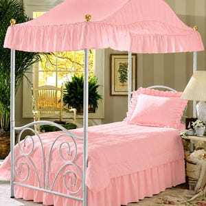 Pu&ograve; includere: Un letto singolo con struttura in metallo bianco caratterizzata da volute sulla testiera e un baldacchino in tessuto rosa con bordo arricciato. Il letto &egrave; vestito con un copriletto trapuntato rosa abbinato, una balza e un cuscino.