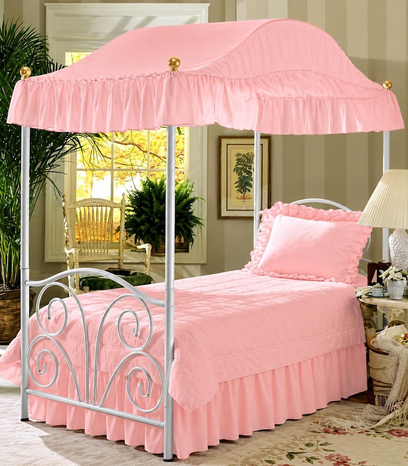 Pu&ograve; includere: Un letto singolo con struttura in metallo bianco caratterizzata da volute sulla testiera e un baldacchino in tessuto rosa con bordo arricciato. Il letto &egrave; vestito con un copriletto trapuntato rosa abbinato, una balza e un cuscino.