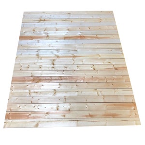 May include: A close-up of a light wood paneling with a natural wood grain. The paneling is made up of horizontal planks of wood.
