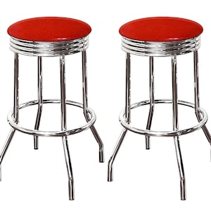 May include: Two red vinyl bar stools with chrome frames. The stools have a round seat and a footrest.