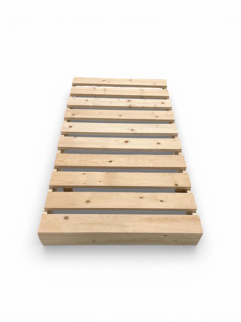 May include: A light-colored wooden pallet with evenly spaced horizontal slats. The pallet is made of unfinished wood and is rectangular in shape. The design is simple and functional, suitable for various uses.