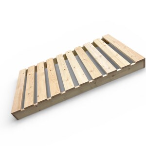 May include: Angled wooden bed frame with a slatted design. The frame is constructed from light-colored wood and features evenly spaced slats. The design is simple and modern, suitable for a minimalist bedroom aesthetic.