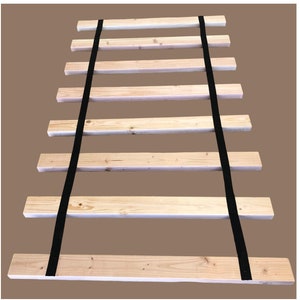 May include: A wooden slat bed frame with black straps to keep the slats together. The frame is made of natural wood and has a rustic look.