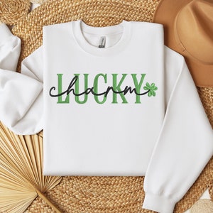May include: White sweatshirt with green and black text that reads "LUCKY charm" with a green shamrock.