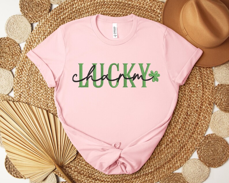 May include: Pink t-shirt with the text "Lucky charm" in green letters with a green four-leaf clover graphic.
