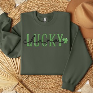 May include: A green sweatshirt with the text "LUCKY charm" in black and green lettering with a shamrock graphic.
