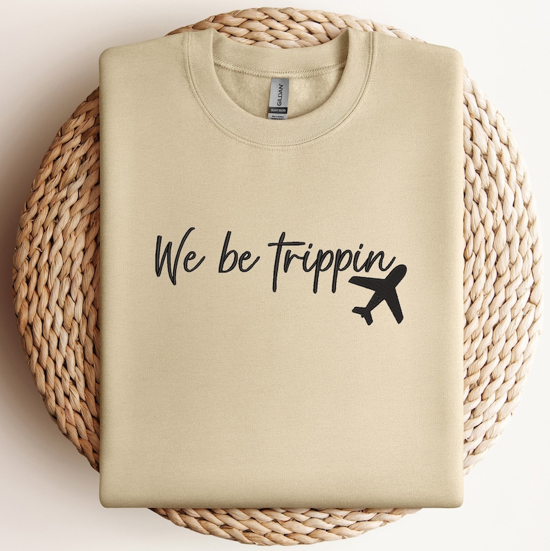 May include: Tan sweatshirt with black text that reads "We be trippin'" and a small airplane graphic.