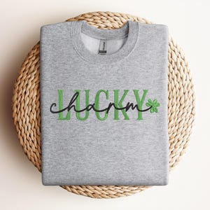 May include: A grey sweatshirt with the text "Lucky charm" in green letters and a green shamrock.