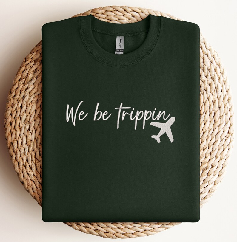 May include: A dark green sweatshirt with the text "We be trippin'" in white lettering and a white airplane graphic.