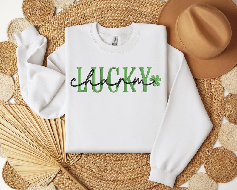 May include: White sweatshirt with green and black text that reads "LUCKY charm" with a green shamrock.