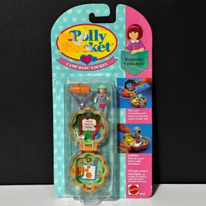 May include: A vintage Polly Pocket Camp Days Locket set, featuring a miniature playset with a tree-shaped locket, a small figure, and accessories. The packaging is teal and pink, with the text "Polly Pocket" and "Keepsake Collection".