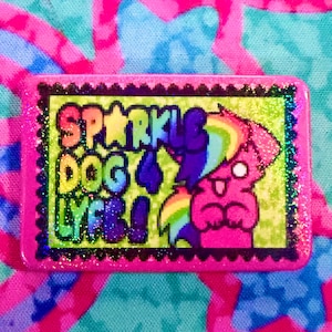 May include: A rectangular pin with a bright pink border and a glittery finish. The center features a lime green background with the text SPARKLE DOG LYFE! in rainbow colors, alongside a pink cartoon dog with a rainbow-colored mane and tail.