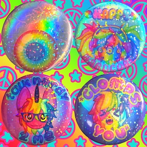 May include: Four vibrant, circular pin badges with glitter and holographic finishes. One displays a rainbow eye design. The others feature cartoon characters and text that reads "Happy", "Talk 2 Me", and "Clowns You".