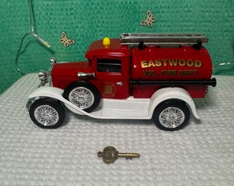 May include: Red and white toy fire truck with a ladder on top and a water tank that says "Eastwood Vol. Fire Dept.". The truck has a key on the ground in front of it.