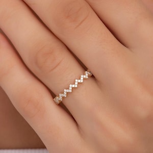 Puede incluir: Un anillo de banda de oro con un patrón en zigzag de pequeños diamantes.