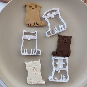 Può includere: Set di sei tagliapasta in plastica bianca a forma di gatto. I tagliapasta sono in varie pose, tra cui seduti, in piedi e dormienti. Alcuni dei gatti hanno maschere per gli occhi.