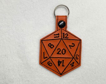 May include: A brown leather keychain shaped like a twenty-sided die with black stitching and numbers 3, 4, 6, 7, 8, 11, 12, 14, 17, 20.
