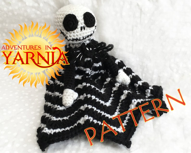 Peut inclure: Poup&eacute;e Jack Skellington au crochet avec une couverture &agrave; rayures noires et blanches. La poup&eacute;e a une t&ecirc;te blanche avec des yeux noirs et un sourire cousu. La couverture a un motif en zigzag. L'image comprend le texte "Adventures in Yarnia" et "Pattern".