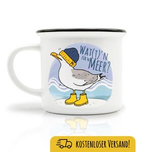 Könnte beinhalten: Weiße Keramik-Tasse mit schwarzem Rand und Henkel. Die Tasse zeigt eine Cartoon-Möwe mit blauer Mütze und gelben Gummistiefeln, mit dem Text "Wat(t)'n Meer?" in Blau. Die Möwe ist vor blau-weißem Hintergrund.