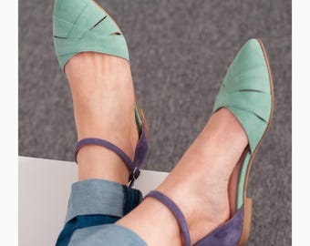 May include: A pair of light green and purple suede ankle strap flats with cutouts. The shoes have a pointed toe and a low heel.