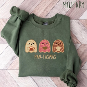 May include: A green sweatshirt with a graphic of three cartoon pan dulce, or sweet bread, with the text "Pan-tasmas".