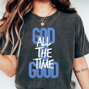 May include: A dark grey t-shirt with a white graphic that reads "God is good all the time" in a blue box.