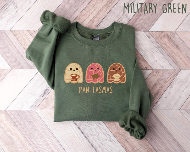 May include: A green sweatshirt with a graphic of three cartoon pan dulce, or sweet bread, with the text "Pan-tasmas".