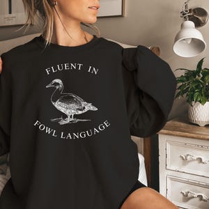 May include: Black sweatshirt with a white graphic of a duck and the text "Fluent in Fowl Language".