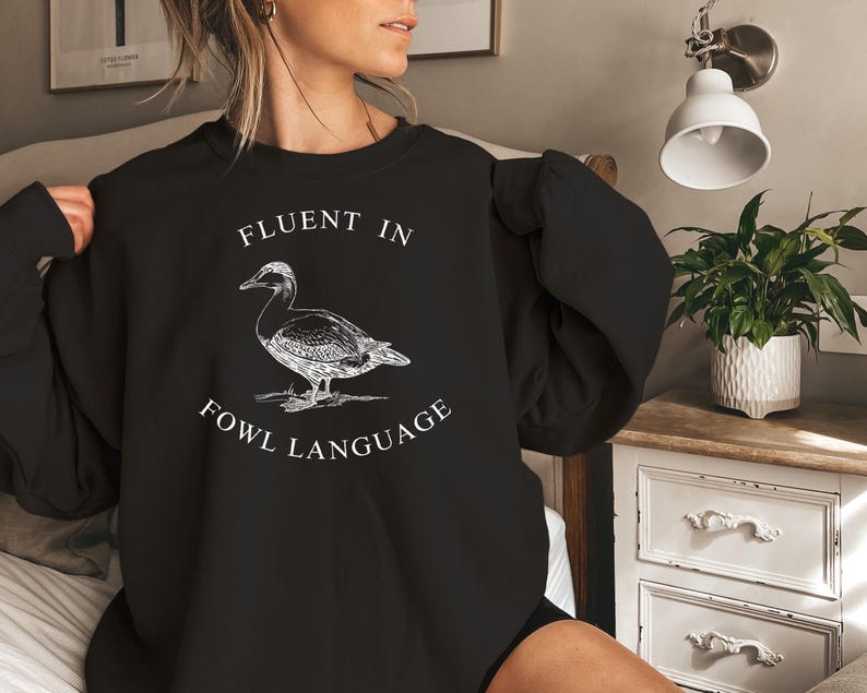 May include: Black sweatshirt with a white graphic of a duck and the text "Fluent in Fowl Language".