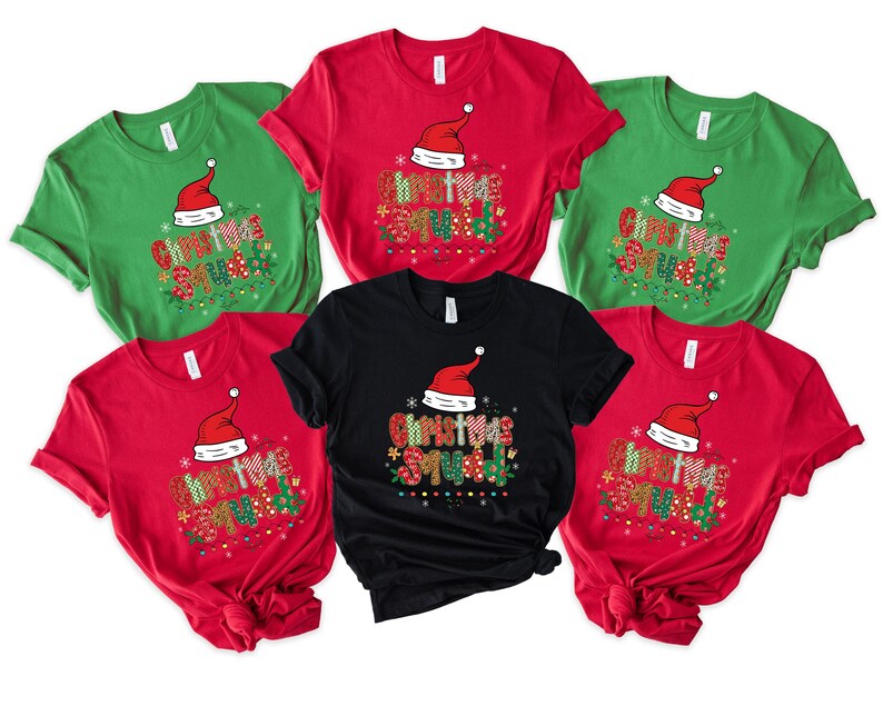 May include: A collection of Christmas Squad t-shirts in red, green, and black. Each shirt features a Santa hat and the words "Christmas Squad" in a colorful, festive design. The shirts are short-sleeved.