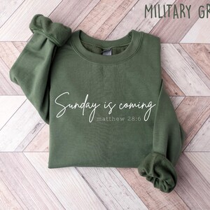 May include: A green sweatshirt with the text "Sunday is coming" and "matthew 28:6" in white lettering.