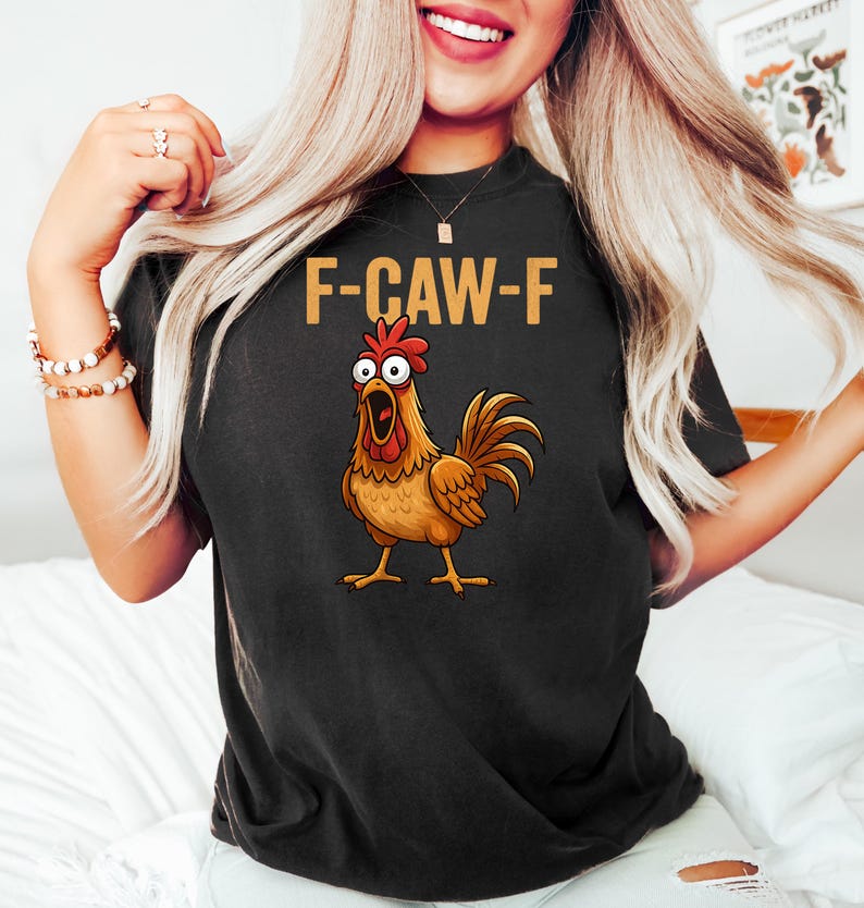 Puede incluir: Camiseta negra con el texto "F-CAW-F" y una ilustraci&oacute;n de un gallo de dibujos animados. El gallo es marr&oacute;n, con cresta roja y pico abierto.